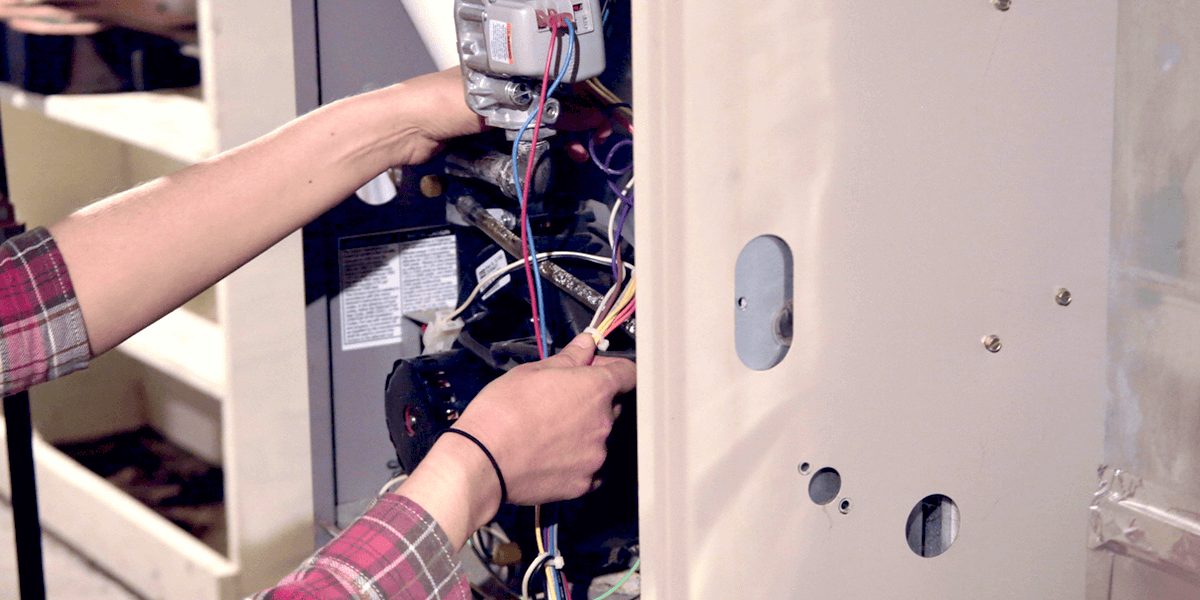 Close-up of someone working on a fuse box for a furnace system